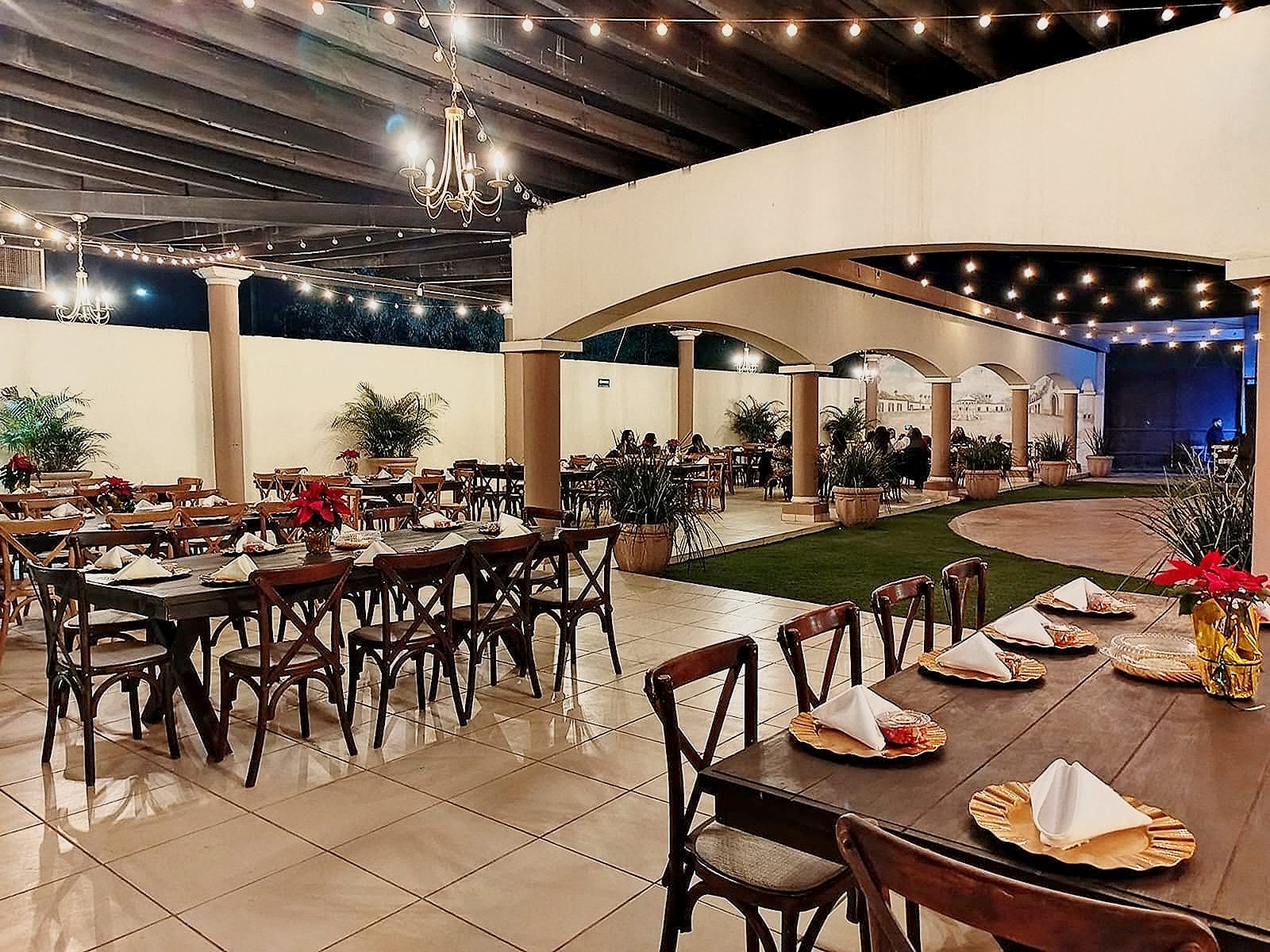 La terraza de arcos montada con mesas largas de madera, lista para un evento