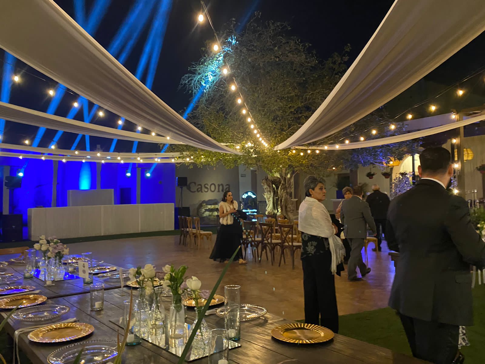 XV años: telas blancas y luces sobre el patio, mesas largas con flores y la pista iluminada