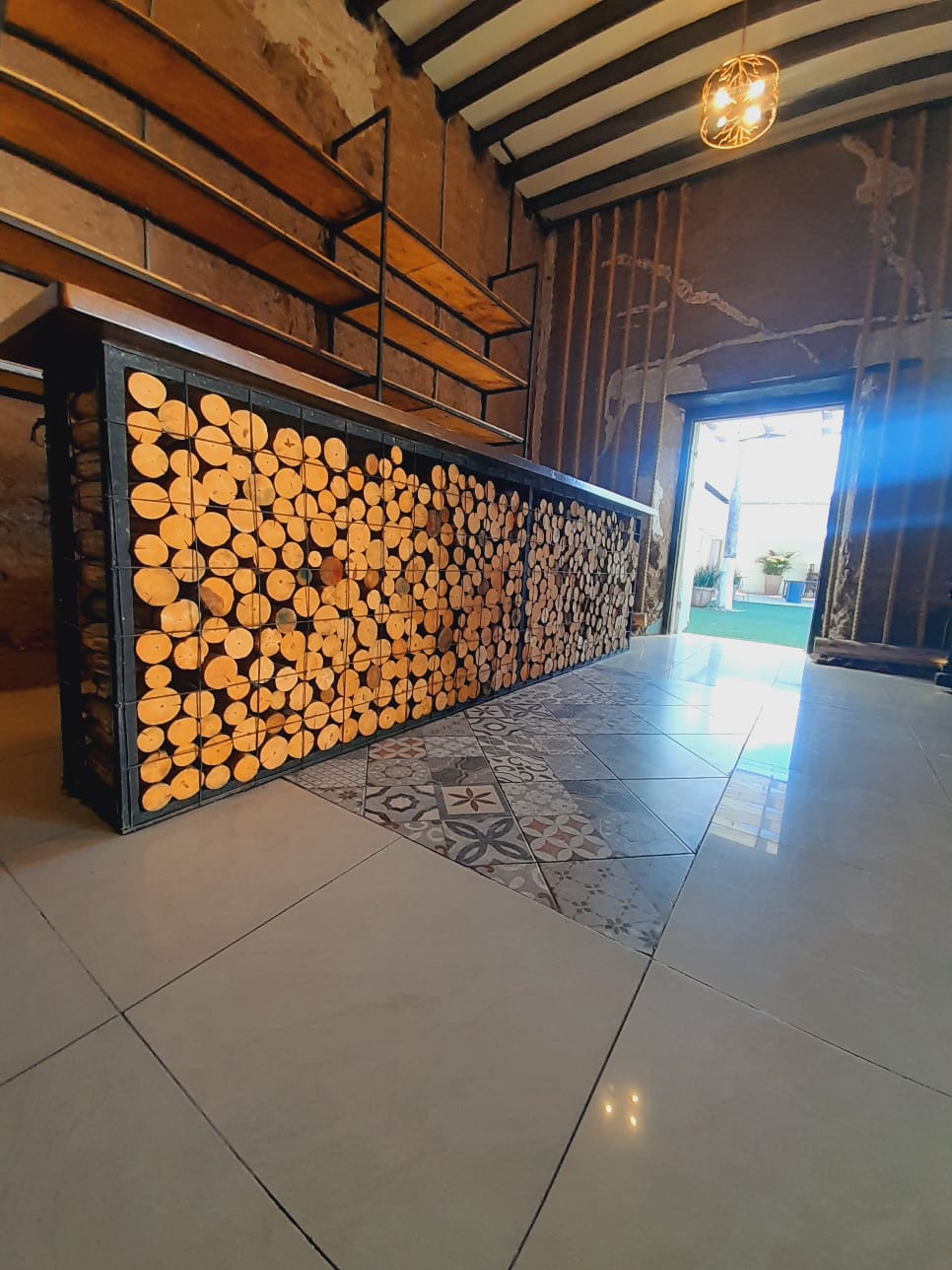 El bar vintage de troncos sobre piso de mosaico, con la puerta abierta al patio