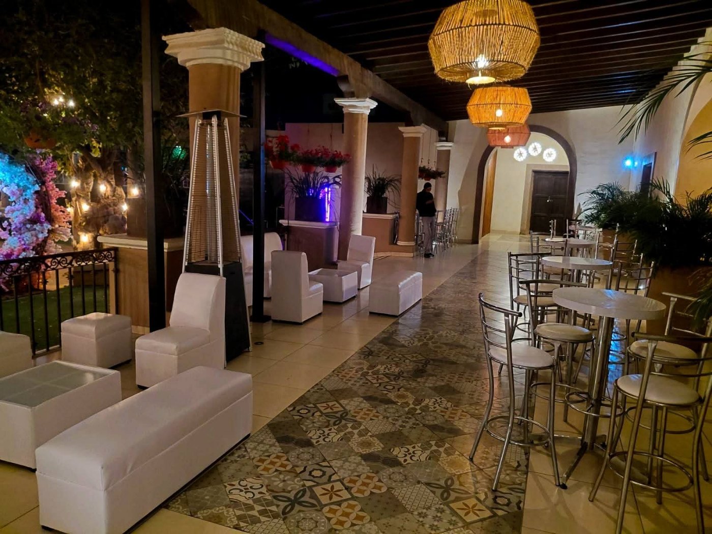 El lobby con sillones blancos, columnas, piso de mosaico y lámparas de mimbre